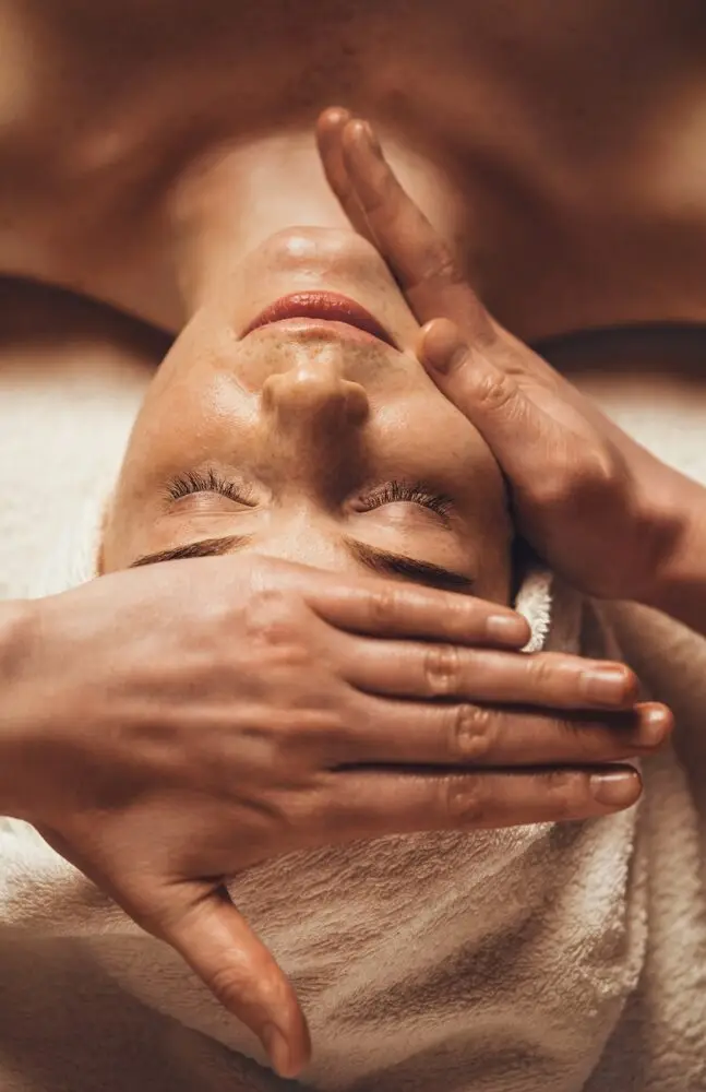 Esthéticienne réalisant un soin de visage à domicile, avec des produits de soin professionnels, illustrant un moment de détente et de bien-être ; soin visage, soin de visage et soin cheveux inclus dans la routine beauté.
